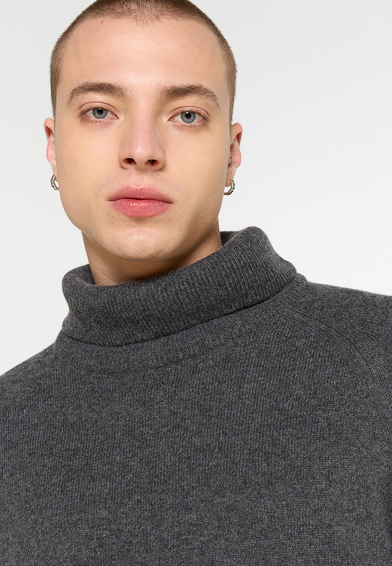 Grauer Rollkragenpullover aus weichem Strickstoff, mit einem hohen, umgeschlagenen Kragen und einer lässigen Passform, der throughout eine subtile Textur aufweist.