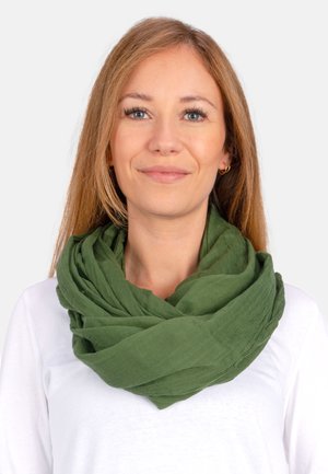 Grüner, strukturierter Schal, der in Schichten angeordnet ist und aus leichtem Material gefertigt ist. Locker um den Hals getragen, ergänzt er ein weißes Oberteil.