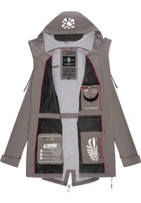 Chaqueta impermeable gris con capucha, con acentos rojos, bolsillos de malla, múltiples etiquetas y un logo decorativo en la parte trasera.