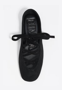 Czarne zamszowe baletki z zaokrąglonym noskiem, z krzyżującym się wzorem sznurowania i teksturowaną czarną wkładką.