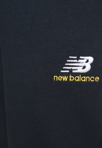 Zwarte stof met een witte en gele geborduurde "new balance" logo, met strakke, moderne designelementen. Zachte textuur, close-up uitzicht.