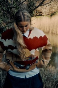 Strickpullover mit einem großen roten und weißen Wolkenmuster, beigem Hintergrund und einem gestickten roten Autodetail an der Taille. Lange Ärmel, gerippte Bündchen.