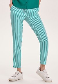 Teal en witte gestreepte broeken met een slim fit, voorzien van een trekkoord in de taille en een gladde stof, gecombineerd met witte sneakers.