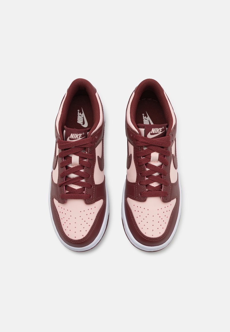 Bordeaux-rote und pinke Sneaker mit synthetischem Obermaterial, durchlöchtem Zehenbereich, flachen Schnürsenkeln und heller Gummisohle. Mit Nike-Branding an den Zungen und Seiten.