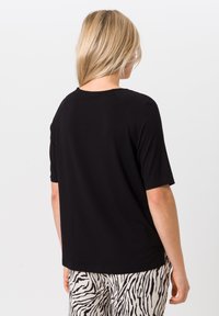 Zwarte t-shirt met korte mouwen en ronde halslijn, gemaakt van gladde stof, met een relaxte pasvorm en raglanmouwen, getoond vanuit de achterkant.