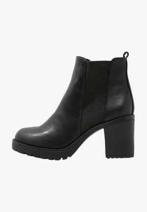 Bottes cheville en cuir noir à finition lisse, avec des panneaux latéraux élastiques et un talon haut épais. Semelle durable avec rainures pour une meilleure adhérence.