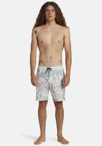 Bordshorts hebben een lichtblauwe tailleband, een trekkoord en een witte basis die versierd is met kleurrijke paisleypatronen.