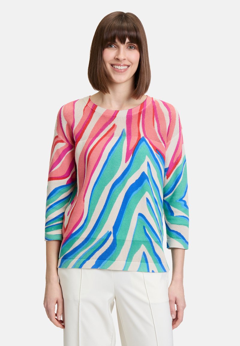 Pull multicolore arborant un motif abstrait de vagues audacieuses, conçu en tricot léger. Il possède des manches trois-quarts et un col rond.