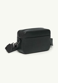 Czarna skórzana torebka crossbody o prostokątnym kształcie, z zamknięciem na zamek i regulowanym paskiem. Posiada minimalną metalową okładkę i gładką teksturę.