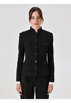 Schwarze, maßgeschneiderte Jacke mit Mandarin-Kragen, ausgestattet mit vorderen Klappentaschen, Knopfverschluss und strukturiertem Schnitt. Glatte Stoffoberfläche.