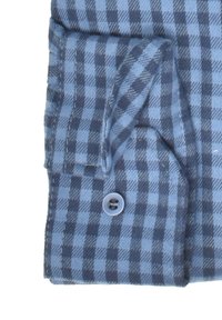 Blau- und grau-karierter Stoff mit einem Knopfdetail. Das Material wirkt strukturiert und zeigt an der Kante eine Faltung mit sichtbaren Nähten.
