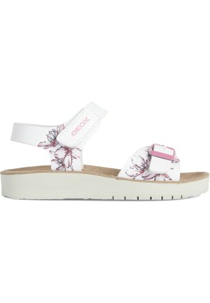 Sandalias blancas con estampados florales, correa ajustable y una plantilla de corcho texturizada. Presentan una suela de plataforma de color claro con estrías.