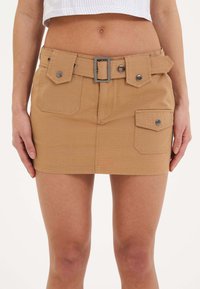 Khaki mini hame dengan permukaan bertekstur, dua saku depan, sabuk dengan gesper segi empat, dan kancing berwarna perak.