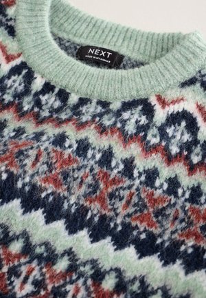 Stickad tröja med mintgrön ribbad krage, prydd med ett flerfärgat zickzackmönster i röda, vita, marinblå och gröna nyanser.
