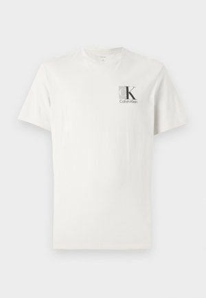 Camiseta de algodón blanca con mangas cortas, escote redondo y un pequeño logo gris en el lado izquierdo del pecho que presenta "ck" y "Calvin Klein."