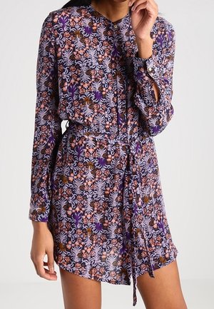 Robe florale violette avec manches longues, ceinture à nouer et poignets à boutons. Présente des motifs complexes en orange, rose et blanc sur un tissu transparent.