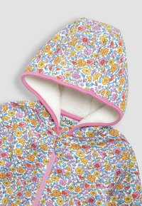 Kvetinová mikina na zips s bielou fleecovou podšívkou, ktorá má ružový lem a jasné žlté, ružové a oranžové kvety na svetlom pozadí.