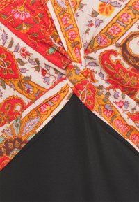 Tissu noir avec un motif floral comprenant des éléments rouges, oranges et roses, design tordu en haut. Bord détaillé avec des motifs complexes.