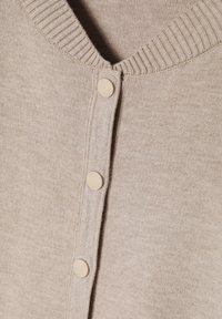 Beige cardigan met een zachte textuur, voorzien van een V-hals, geribbelde halslijn en vier beige knopen aan de voorkant voor sluiting.