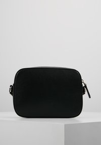 Schwarze rechteckige Tasche aus strukturiertem Material. Verfügt über einen Reißverschluss und einen verstellbaren Trageriemen. Klare Linien mit minimalen Hardware-Elementen.