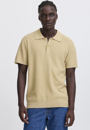 Beige polo met korte mouwen, een gestructureerde breiwijze, een brede kraag en een knoopsluiting met drie knopen. Afgewerkt met geribbelde manchetten en zoom.