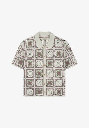 Gehaakte cardigan met korte mouwen en knopen aan de voorkant, met een rasterpatroon van paarse en groene bloemenvierkanten op een crèmekleurige achtergrond.