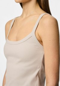 Ribbed tank top w jasnym beżu, z wąskimi ramiączkami i kwadratowym dekoltem, wykonany z miękkiego, elastycznego materiału.