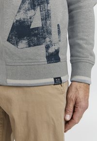 Grauer Sweatshirt mit einem großen, destruierten navyblauen Nummer "4" Druck. Verfügt über gerippte Bündchen und Saum, mit einem Logotag am unteren Ende.