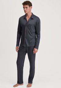 Heren donkergrijze pyjama set, lange mouwen met knoopsluiting, voorzien van een borstzak, contrasterende rode bies en bijpassende broek, gemaakt van zacht materiaal.