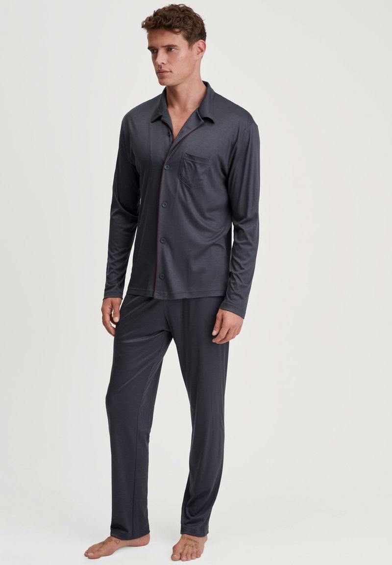Heren donkergrijze pyjama set, lange mouwen met knoopsluiting, voorzien van een borstzak, contrasterende rode bies en bijpassende broek, gemaakt van zacht materiaal.