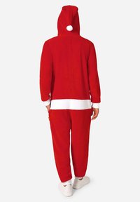 Rode fleece onesie met capuchon, witte bies en een pompon bovenop. Losse pasvorm met manchetten en een zakdetail. Knusse stof.