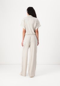 Ensemble léger à rayures en crème et bleu marine, comprenant un haut à col et manches courtes et un pantalon large avec une taille élastique.