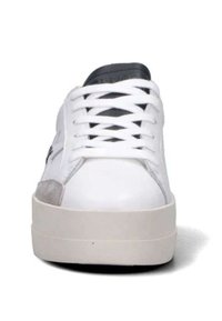 Sneaker bianchi a taglio basso con suola spessa, lacci bianchi, linguetta nera e dettaglio in pelle scamosciata grigia sul lato anteriore, visto frontalmente.