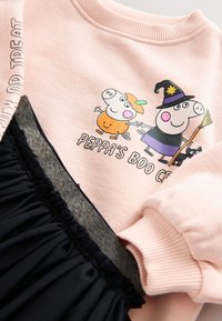 Rosa sweatshirt med tecknade figurer, svart kjol med veckad textur, mjukt tyg och ribbade muddar. Har Halloween-tema grafik.