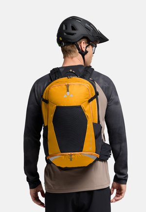 Zaino arancione e nero con una superficie texturizzata, spallacci regolabili e una tasca con zip. Sono visibili dettagli riflettenti nella parte anteriore.