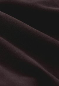 Stretchtyg i djup svart med mjuk textur, som har subtila vågor och veck, vilket visar på flexibilitet och ett mjukt fall.