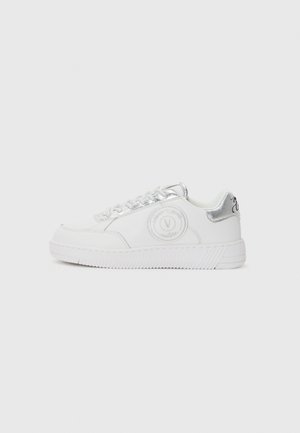 Hvite lavtopp sneakers med sølvmetalliske detaljer, snøring foran, preget logo på siden og merket såle.