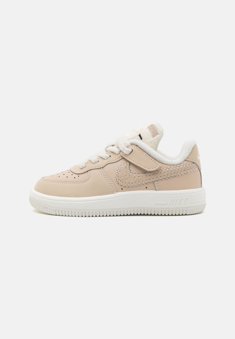 Nike Air Force 1-sneakers i ljusbeige läder med vit sula. Har en sydd swoosh och mjuka detaljer på tungan.