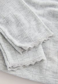 Tissu gris à motifs avec des rayures verticales et de petits losanges, fini avec une délicate bordure en dentelle le long des bords.