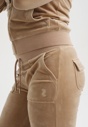 Joggers in velluto beige con vita aderente, tasche laterali e dettaglio logo ricamato. Texture liscia e fit affusolato.