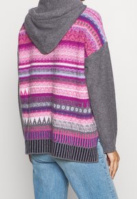 Hooded sweater with pink, purple, and gray striped patterns; textured knit on the back; gray sleeves; ribbed hem and cuffs; relaxed fit.