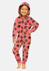 Bambino sorridente che indossa un tuta con cappuccio rosa decorata con facce di cani cartoon, in piedi a piedi nudi con una mano sui fianchi, davanti a uno sfondo neutro.