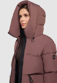 Chaqueta puffer con una capucha profunda, hecha de un tejido suave en color malva, con cierre de cremallera y acentos de hardware en negro.
