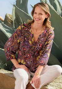Mehrfarbige Button-Up-Bluse mit lebhaften Paisleymustern in Lila, Pink und Grün, mit Dreiviertelärmeln und lässiger Passform.