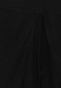 Le tissu en lin noir présente un pli central avec une texture douce. Le design est simple et discret, sans motifs ni ornements supplémentaires.