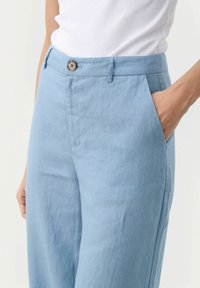 Lichtblauwe linnen broek met een zachte textuur, voorzien van zijzakken, een knoop waistband en een losse pasvorm, geschikt voor casual draag.