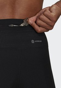 Pantaloni sportivi neri con un motivo a griglia testurizzato, dotati di una tasca con zip sicura, branding riflettente e tecnologia AEROREADY traspirante.
