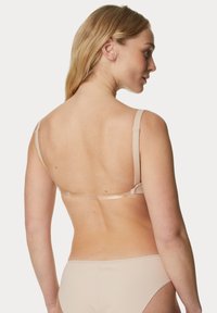 Beige bh met verstelbare bandjes en haaksluiting, gladde textuur, minimalistisch ontwerp, naadloze achterkant en zachte stof.
