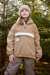 Brun fleece-pullover med en hvid stribe, lynlås lukning og stjernesignet. Båret med grå bukser, sat mod grønt forgrund.