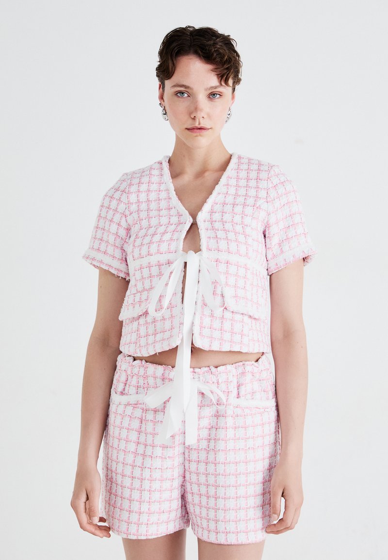 Kortermet, crop topp og matchende shorts i rosa og hvit rutete stoff, med frontknute og teksturert overflate.